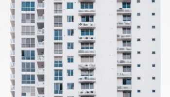 A sleek, modern high-rise building with a glass facade and multiple balconies, showcasing urban architecture.