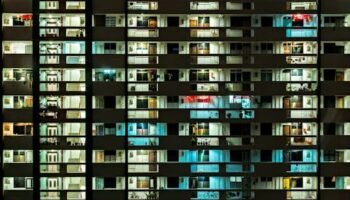 Night view of a modern apartment building with illuminated windows, showcasing urban life.